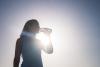Woman drinks water under summer sun.