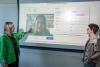 Xingyu Li and Alexandra Teixeira Riggs stand in front of a screen showing an emotion AI analysis of Li's facial expression.