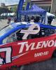 Red race car sporting a white ribbon for lung cancer awareness