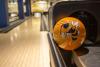 A yellow bowling ball with Buzz on it sits in front of a bowling lane