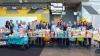 1.	A photo of a group of people standing behind a table full of packaged food. The group is smiling and represents a diverse crowd of faculty and staff.