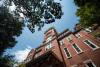 Tech Tower at the Georgia Institute of Technology, a red-brick academic building with white trim and arched windows, rising above surrounding trees under a blue sky.