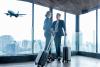 Two people in an airport with a plane flying in the background