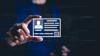 A hand holds up a digital identification card. The card has the silhouette of a man wearing a suit and tie. 