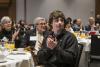 Student clapping in the foreground at a table with donors sitting behind him