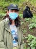A woman wearing a mask stands near a gorilla.