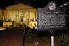 Nighttime view of the Historic Academy of Medicine with its six doric columns and the historic marker in the foreground