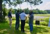 Five men stand in a sunny yard overlooking the marsh in deep conversation. From left to right: South Carolina Aquarium Chief Executive Officer Kevin Mills, John Carr, Chairman of the South Carolina Aquarium Conservation Committee Jonathan Zucker, former South Carolina Aquarium Director of Conservation Albert George, and School of Biological Sciences Professor Joel Kostka.