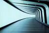 The photograph is of a curving corridor illuminated in light blue with curving black stripes along the ceiling and right side of the hallway. Used under a creative commons license. 