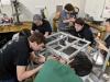 Seven members of the RoboJackets build various parts of a robot's aluminum frame.