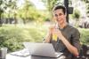 Man on laptop smiles while drinking juice
