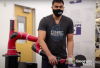 A Ph.D. student at Georgia Tech helps a robot arm learn to return a ping pong ball