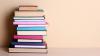 A stack of books against a tan wall.