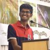 Vikas Madhav Nagarajan smiles while presenting at a lectern on birds in India.