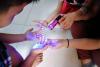 A black light shows "germs" on children's hands. 