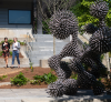 Image of two people walking outside next to sculpture.