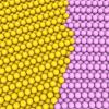 A graphic with yellow and pink spheres in a crystal formation, representing a grain boundary between two abutting grains